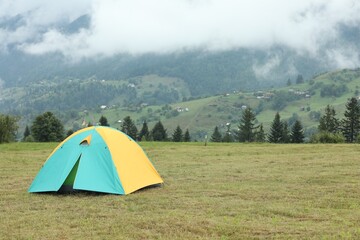 Camping tent on green grass in mountains, space for text