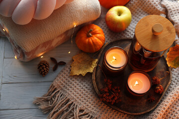 Burning candles, freshly brewed tea, sweaters and autumn decor on wooden table