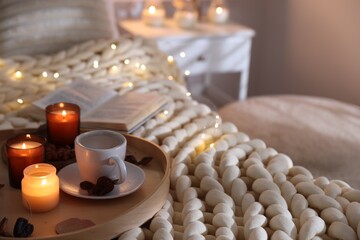 Burning candles, lights, coffee and decor on bed indoors. Autumn atmosphere
