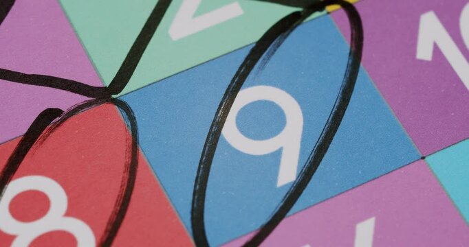 Close-up image of a colorful bingo card featuring numbers with the number 9 circled in black marker. Close-Up of a Bingo Card with the Number 9 Circled in Black Marker