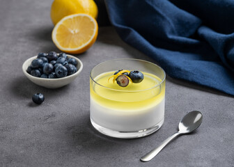 Creamy lemon panna cotta with blueberries in a glass with fresh berries, citrus fruits and napkin...