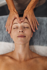 A woman receives a relaxing facial massage in a tranquil spa setting with soft warm lighting