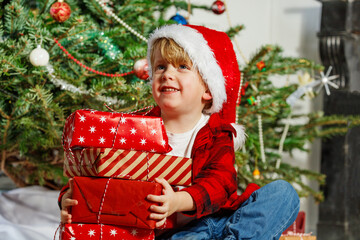 Young boy wearing Santa hat, hold and enjoy Christmas gifts