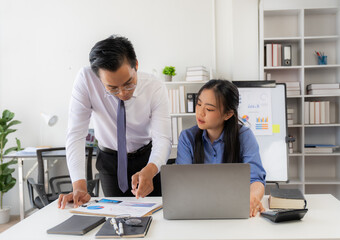 Obraz premium Guiding Growth: A seasoned professional mentors a younger colleague, fostering teamwork and knowledge transfer in a modern office environment.