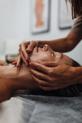Naklejka premium A woman receives a relaxing facial massage in a tranquil spa setting with soft warm lighting