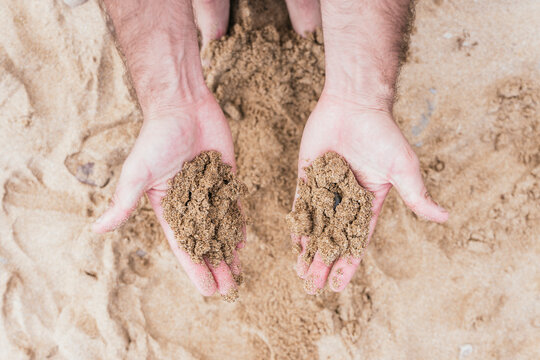 Anonymous hands holding sand, close-up view in a natural setting