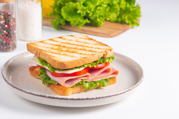 Close-up of two sandwiches with bacon, salami, prosciutto and fresh vegetables on rustic wooden cutting board. Club sandwich concept