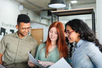 Three business office colleagues reviewing important documents standing together in a professional workspace