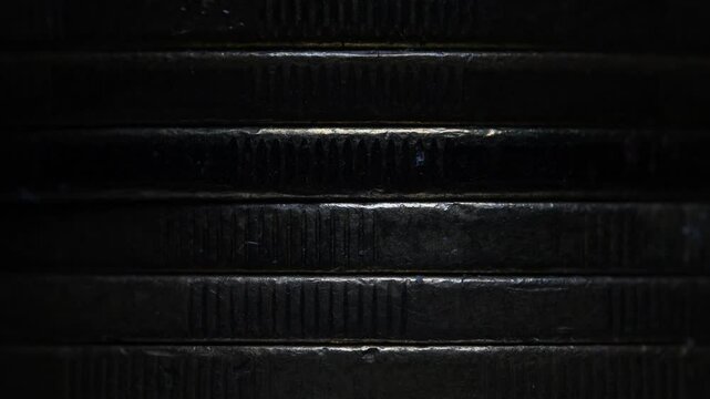 Stack of brown coins in close-up, texture of old coins, dark background, light movement, metal texture
