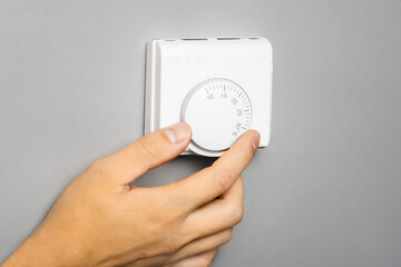 Fototapeta premium Man adjusts temperature on thermostat, stabilizing temperature in house. Increasing temperature in house