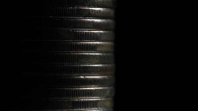 Stack of brown coins in close-up, texture of old coins, dark background, light movement, metal texture