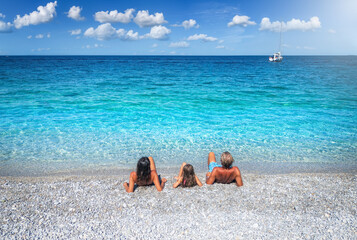 Rear view of a family lying on a beach with turquoise sea for the summer holiday vacations with...