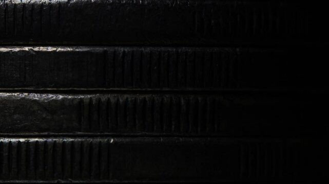 Stack of brown coins in close-up, texture of old coins, dark background, light movement, metal texture
