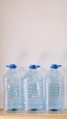 Minimalist Trio of Water Containers
Three large plastic water containers neatly arranged in a row against a plain white background. The simplicity of the composition and soft lighting give the image a