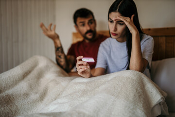 Worried couple is looking positive pregnancy test 