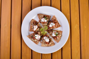 Mexican nacho chips baked with chicken, black beans and cheese on a plate top view