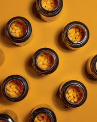 Top view of bottles with yellow capsules arranged on orange