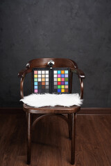 ColorChecker Passport on wooden chair in dark studio. Rainbow color palette for photographer