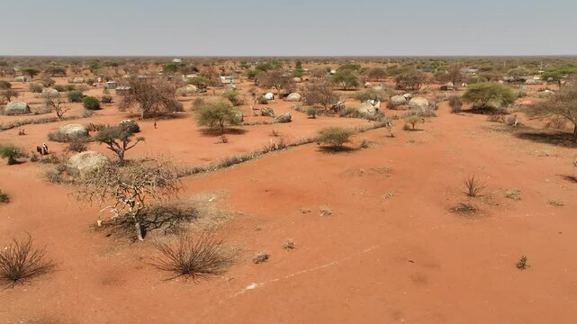 Aerial view of a traditional village with rustic huts surrounded by dry savannah and sparse vegetation, Wajir, Kenya.