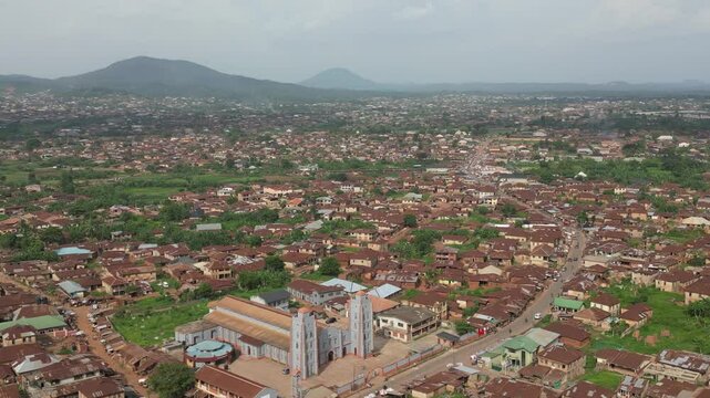 Aerial view of beautiful urban sprawl with traditional buildings and greenery amidst hills and mountains, Ife, Nigeria.