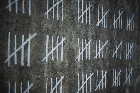 counting days on a concrete wall - handwritten lines of white chalk