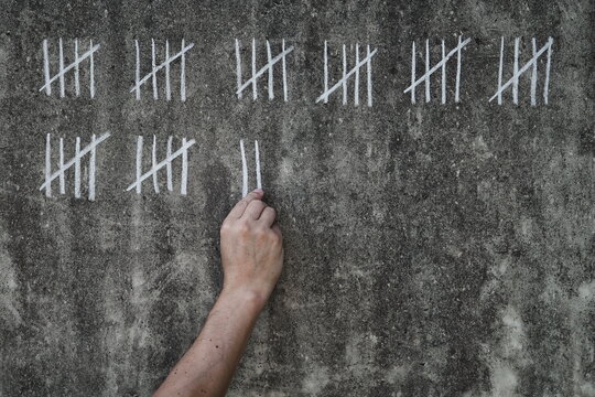 counting days on a concrete wall - handwritten lines of white chalk