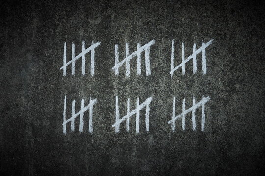 counting days on a concrete wall - handwritten lines of white chalk