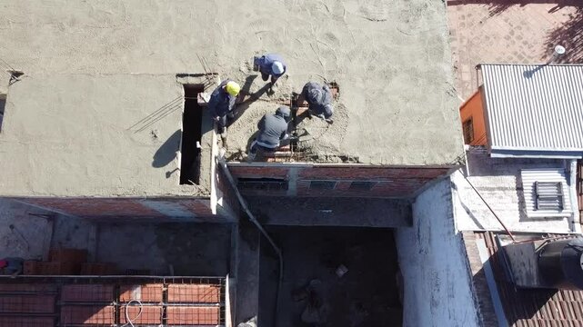 Men working in construction industry. Masons placing cement on the roof of a house. Construction workers making cement with a hose to make the roof slab of a building.