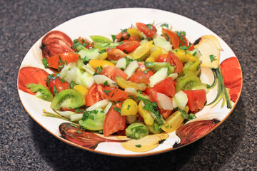 Tomatoes salad with zucchini and parsley inside a decorated plate