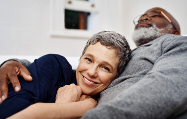 Relax, smile and senior couple hug for love, care and support in living room at home. Interracial, man and woman embrace for connection in relationship, commitment and loyalty to partner in marriage