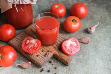 Homemade tomato juice in jars, fresh tomatoes, garlic and spices on the table
