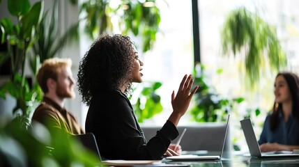 A diverse team meeting with engaged participants discussing ideas in a modern workspace filled with plants.