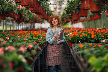 Young florist enjoying flower galore in her modern greenhouse.