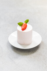 Vegan Strawberry pudding, Panna Cotta cylindrical shape.  On a plate. Close up. Light gray background