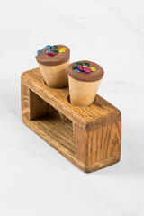 Vegan dessert. Waffle cones, with chocolate nut cream and colored dragees. On a wooden serving stand