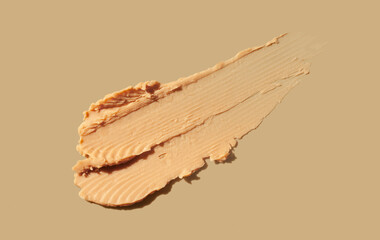 Peanut butter or cosmetic make-up face care beige primer smoothing base isolated on beige texture or 