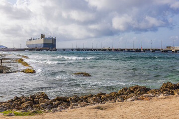 Cargo ship moored at pier on Caribbean island of Curacao on cloudy day. 