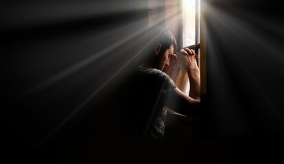 Sad soldier praying at the window