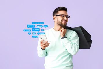 Handsome man with mobile phone and shopping bags on lilac background