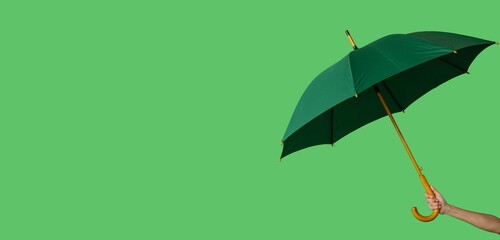 Hand holding umbrella on green background with space for text