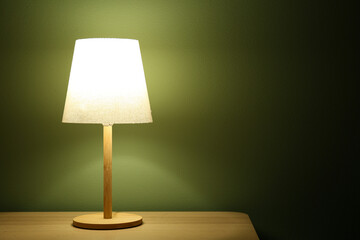 Glowing lamp on wooden table in dark room