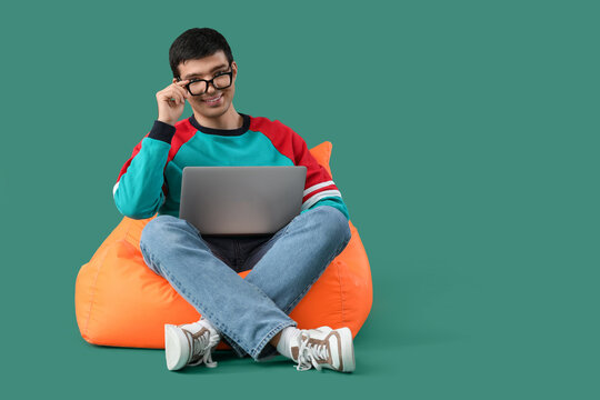 Male programmer with laptop sitting on green background
