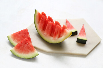 Board with pieces of fresh watermelon on white background