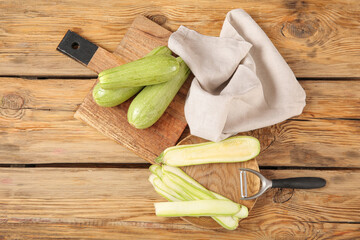 Board and plate with fresh green zucchini on wooden background