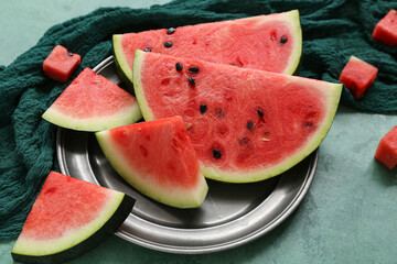 Plate with pieces of fresh watermelon on green background