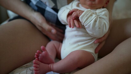 Newborn baby resting in a parent's lap, dressed in a white onesie, showing a close bond and tender care in a cozy and nurturing environment