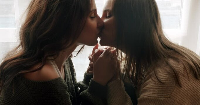 The women approach each other, touch each other tenderly and romantically. The girls look into each other's eyes and smile beautifully. sweet kiss. Close up look at face.Embrace and holding each other