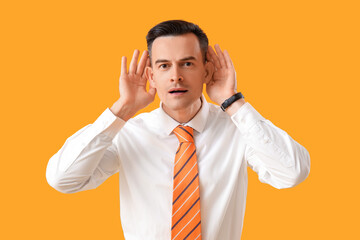 Young businessman with hearing problem on yellow background