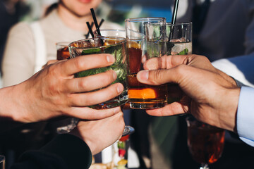 Group of guests celebrate and raise glasses, cheering with alcohol glasses with wine and champagne...