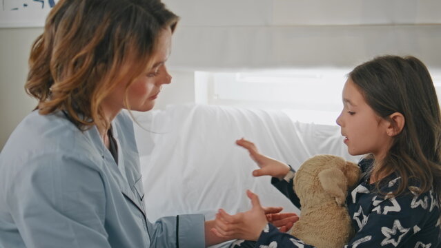 Upset girl contemplating problems to mother at bedding closeup. Sad little child